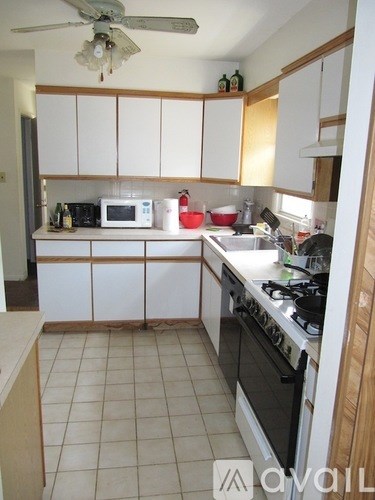 A kitchen with white cabinets and a fan on the ceiling.