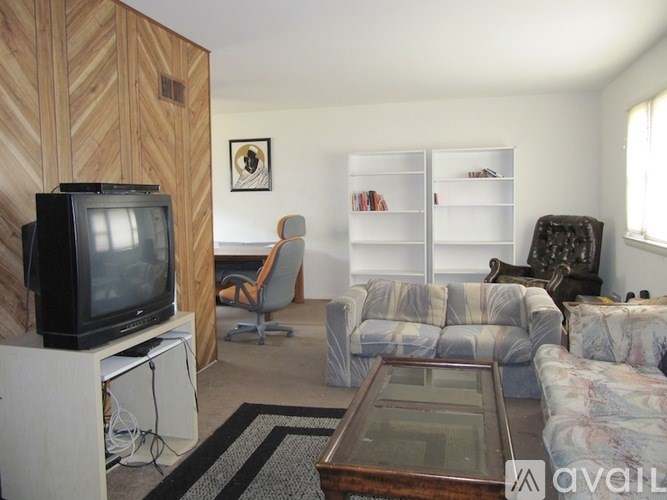 A living room with a television, a chair, a couch, and a coffee table.
