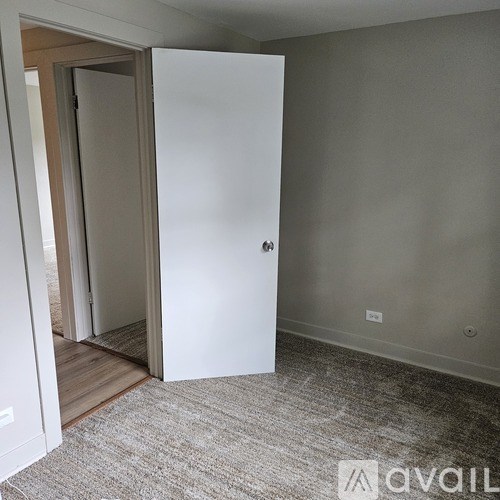A room with a white door and carpeted floor.