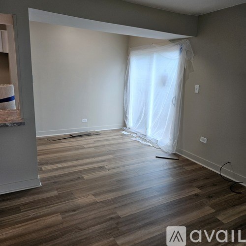 A room with wooden flooring and a window covered with white curtains.