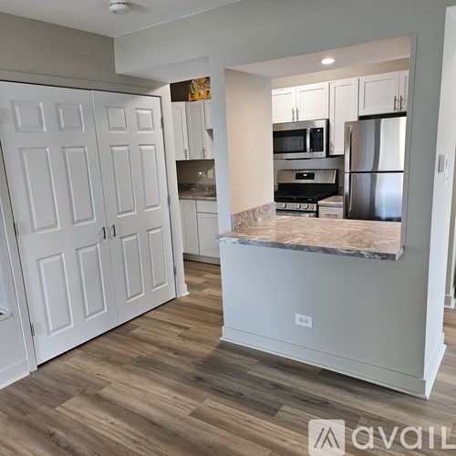 A kitchen with white cabinets and a marble island.