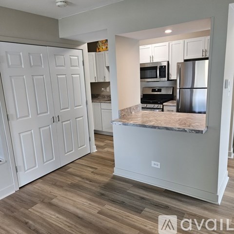 A kitchen with white cabinets and a marble island.