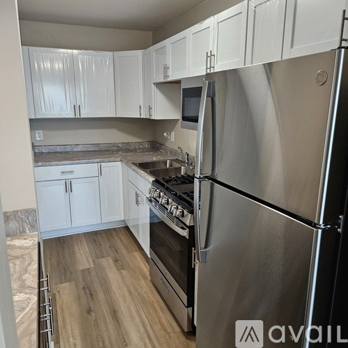 A kitchen with white cabinets and a stainless steel refrigerator.