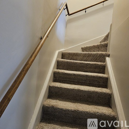 A staircase with a beige carpet and wooden handrail.