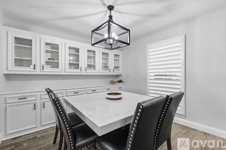 A dining room with a table set for two and a chandelier hanging from the ceiling.