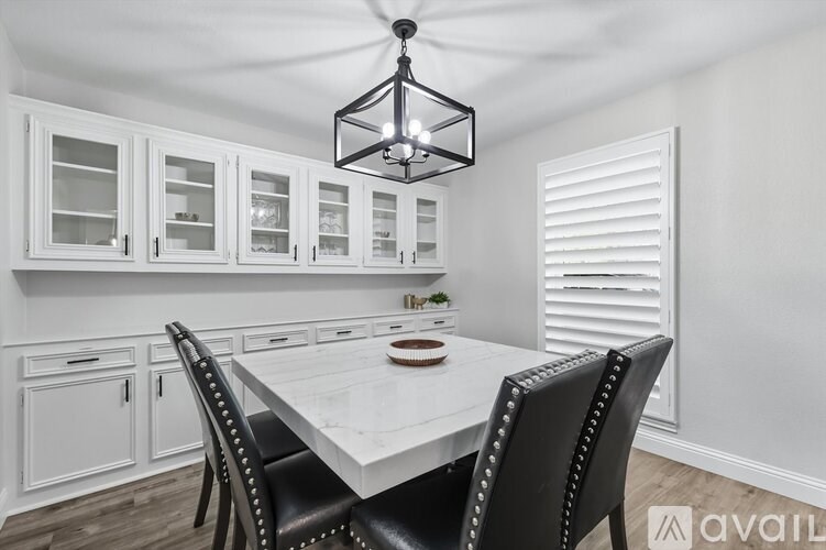 A dining room with a table set for two and a chandelier hanging from the ceiling.