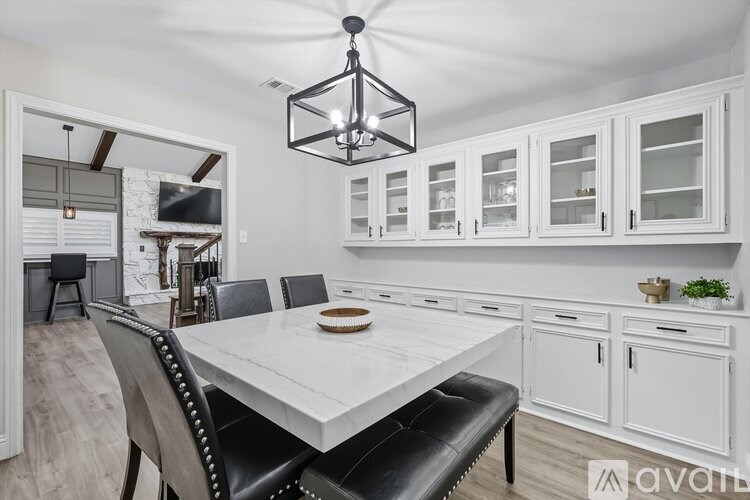 A modern dining room with a white table and black chairs.