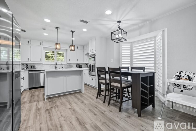 A modern kitchen with white cabinets and wooden floors.