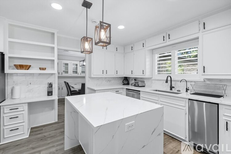 A modern kitchen with white cabinets and a marble island.