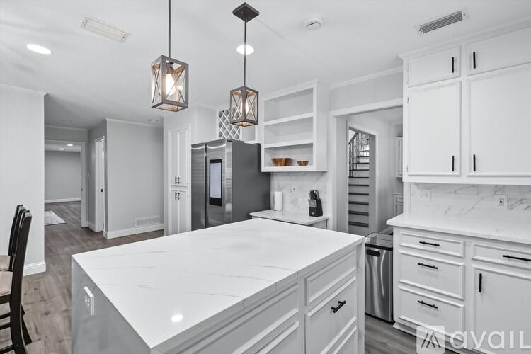 A kitchen with white cabinets and a white island.