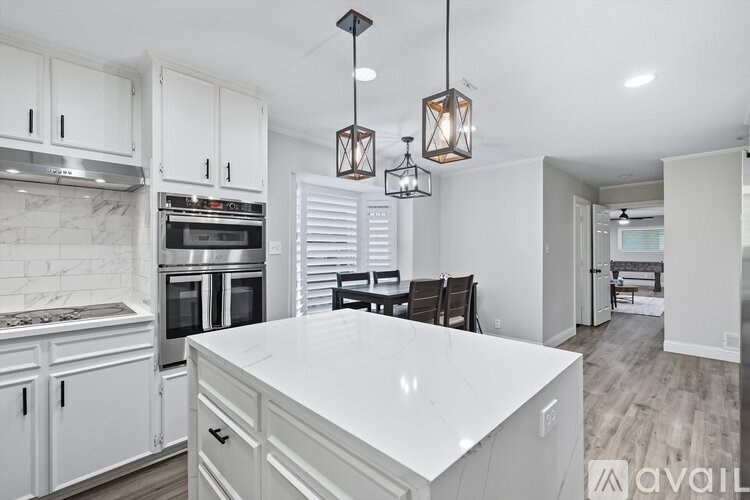 A kitchen with white cabinets and a marble backsplash.
