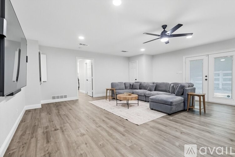 A spacious living room with a grey sofa set and a wooden floor.