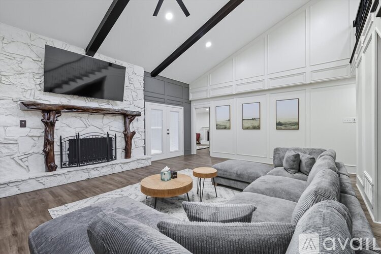 A living room with a grey couch and a fireplace.