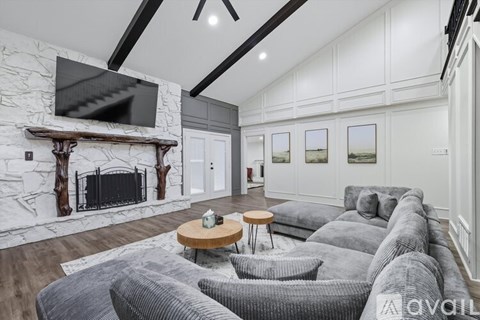 A living room with a grey couch and a fireplace.
