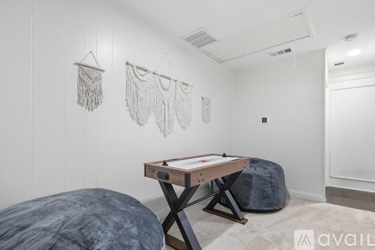 A room with a table, bean bag, and macrame wall hangings.
