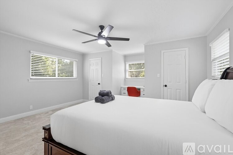 A bedroom with a large bed and a ceiling fan.