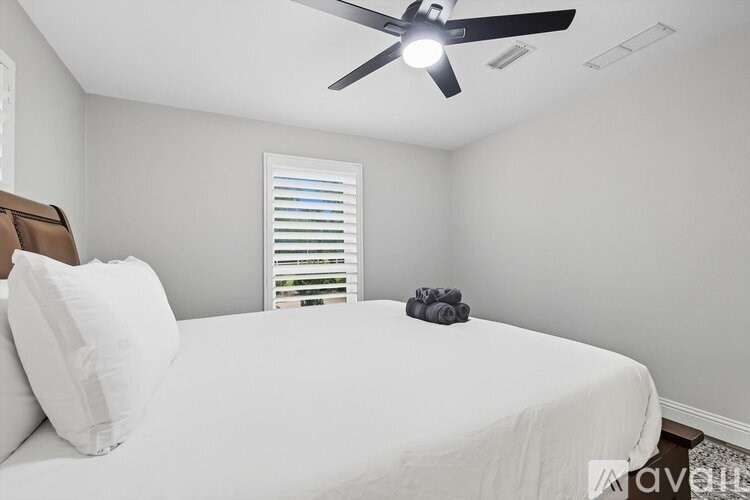 A bedroom with a white bed and a ceiling fan.