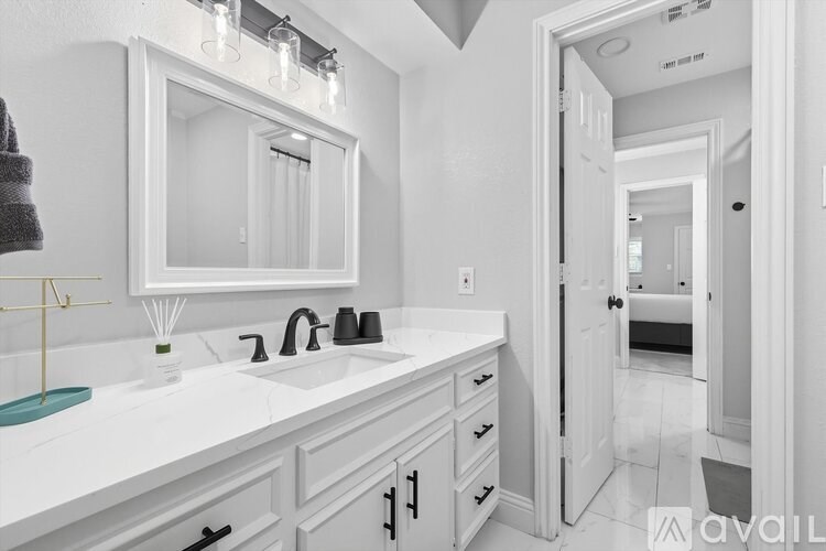 A bathroom with a white sink and mirror.
