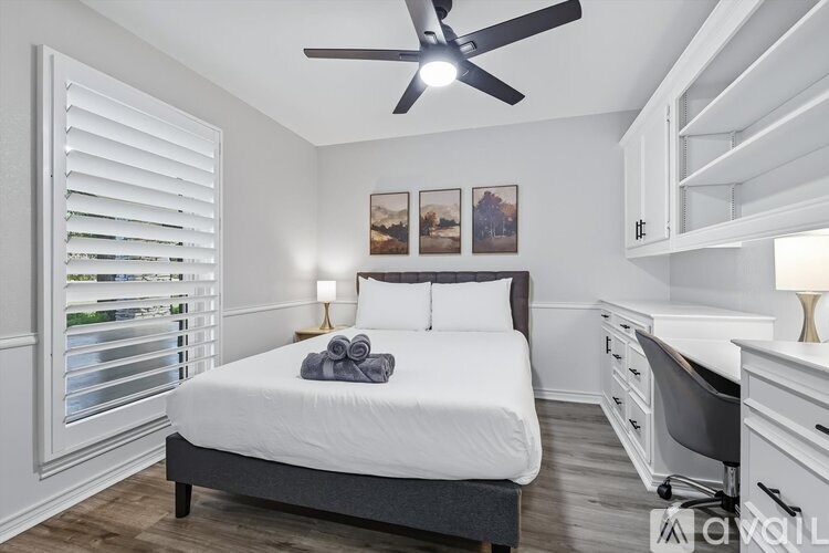 A bedroom with a bed, chair, and pictures on the wall.
