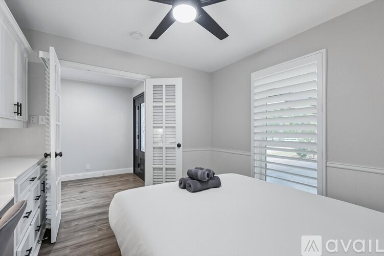 A bedroom with a bed, dresser, and a ceiling fan.
