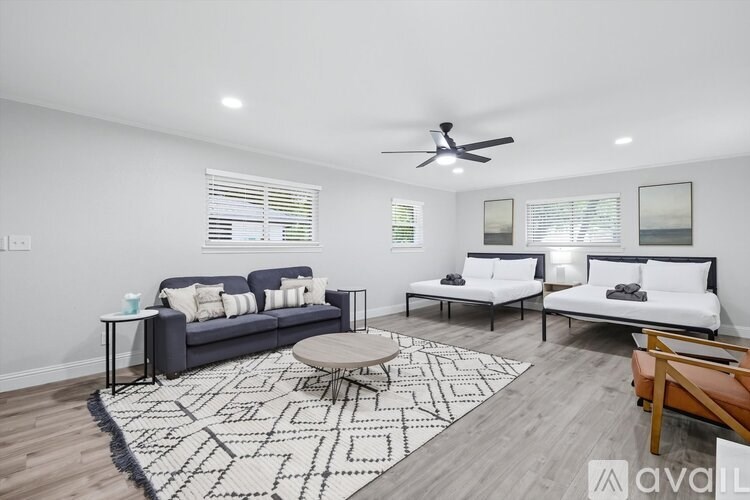 A living room with a grey couch, a white sofa, a round table, and a rug with a geometric pattern.