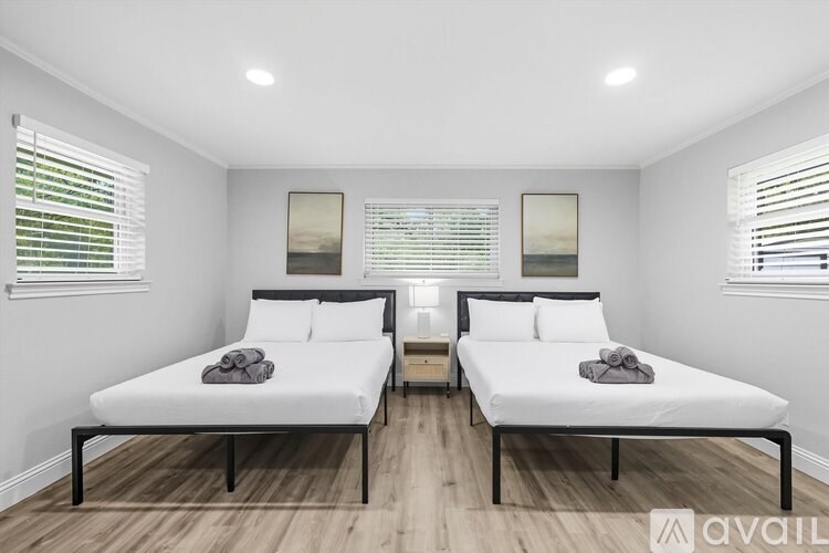 Two beds in a room with white walls and wooden floors.