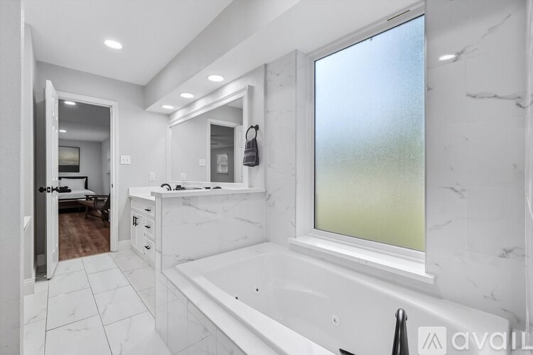 A bathroom with a large tub and a window.