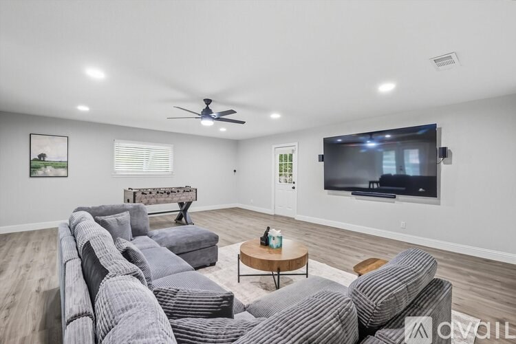A living room with a grey couch and a television on the wall.