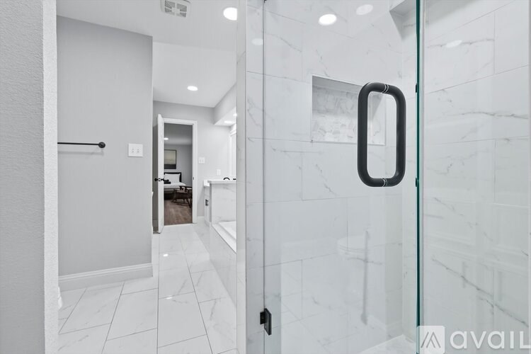 A bathroom with a glass door and a white tiled floor.