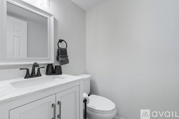 A bathroom with a toilet, sink, and mirror.