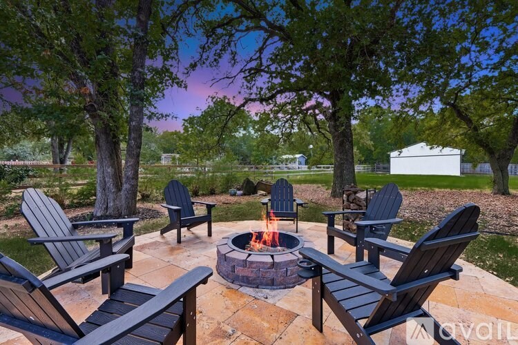 A fire pit surrounded by chairs in a backyard.