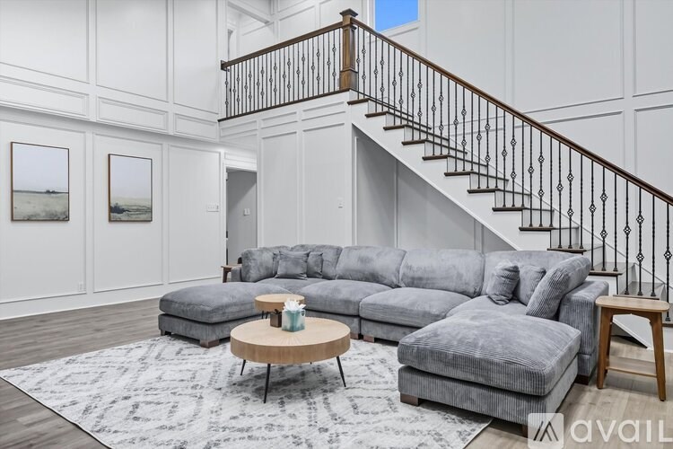A living room with a grey sofa, a coffee table, and a staircase.