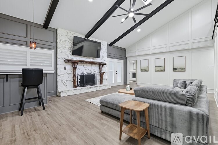 A modern living room with a grey couch, a fireplace, and a television.