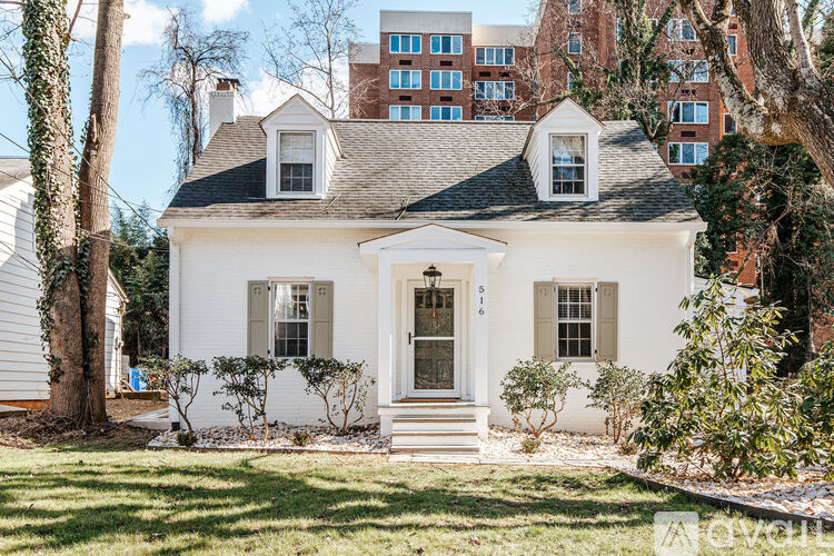 A white house with a black roof and a brown door.