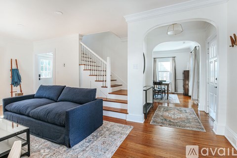 A living room with a blue couch and a glass table.