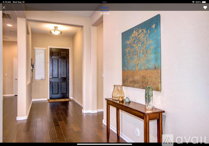 A hallway with a painting on the wall and a table with vases on it.