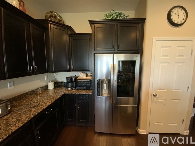 A kitchen with black cabinets and a stainless steel refrigerator.