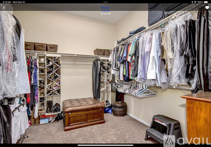 A room with a large closet full of clothes and a bench in the middle.