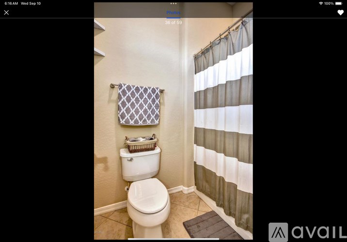 A bathroom with a toilet, a basket on the toilet seat, and a shower curtain.