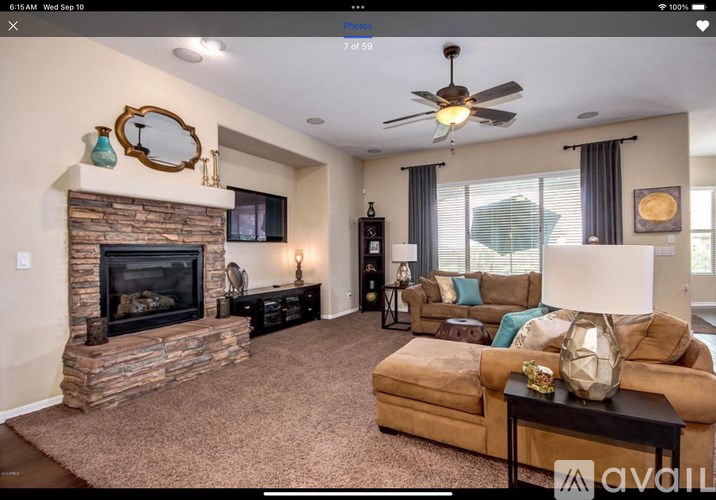 A living room with a stone fireplace and a flat screen TV mounted on the wall.