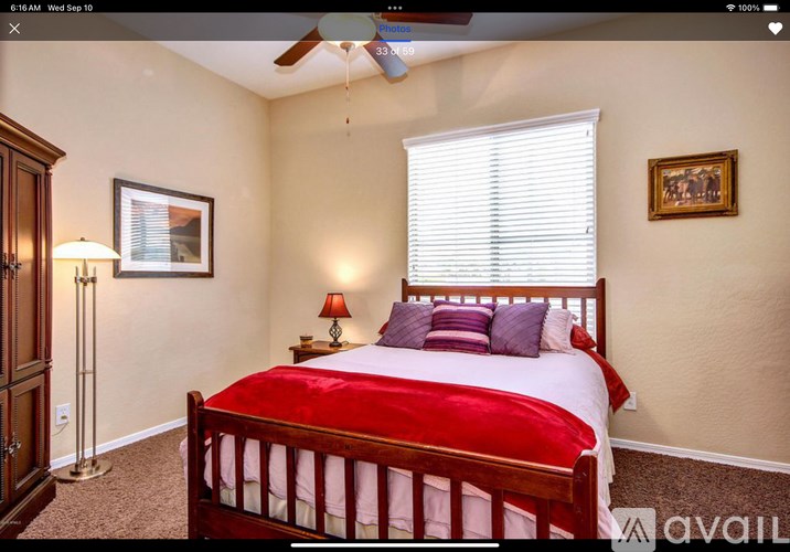 A bedroom with a bed, a ceiling fan, and a painting on the wall.
