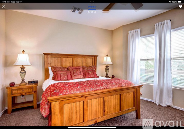 A bedroom with a large bed and two lamps.