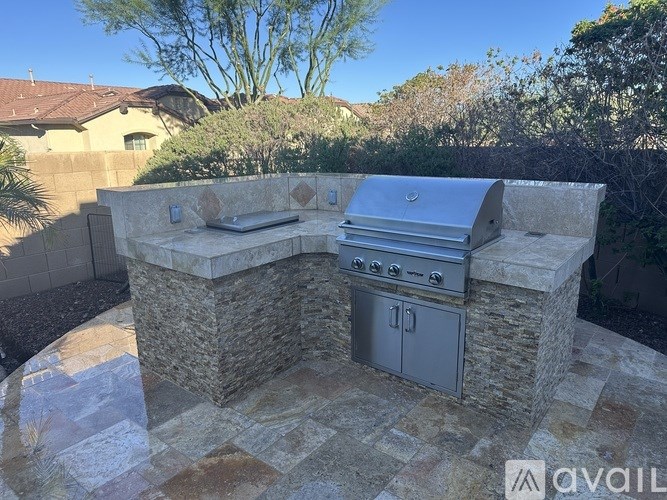 A stone outdoor kitchen with a grill and oven.