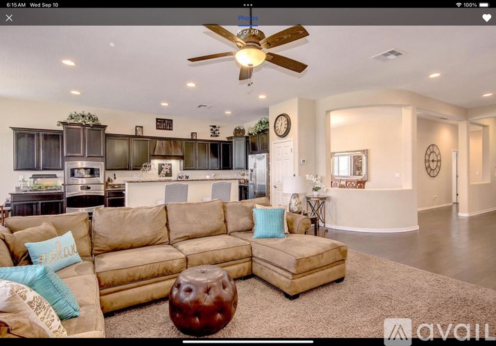 A living room with a beige sofa and a ceiling fan.