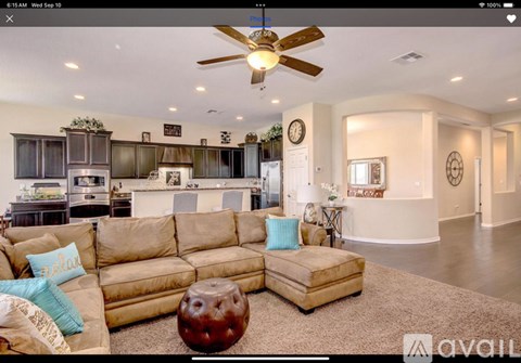 A living room with a beige sofa and a ceiling fan.