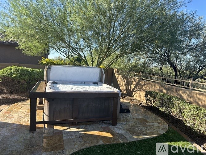 A hot tub sits on a patio surrounded by a stone border.