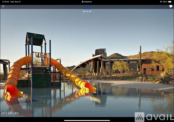 A playground with a yellow slide and a pool in the foreground.