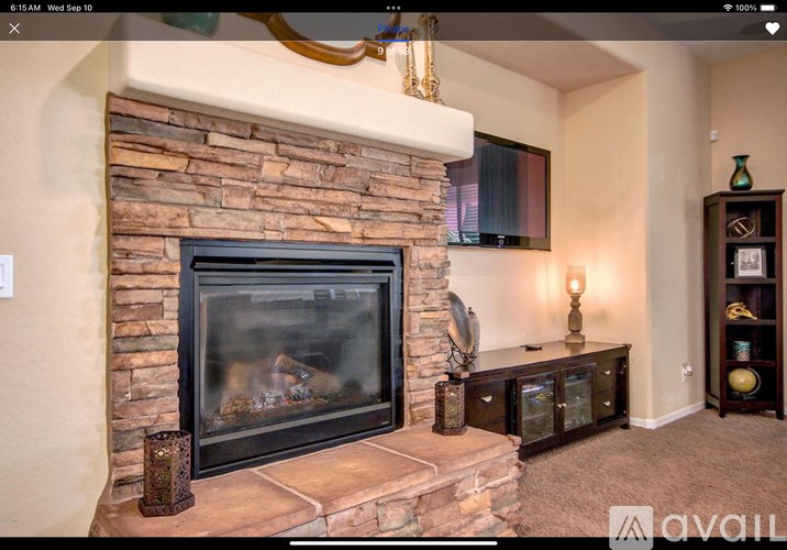 A stone fireplace with a fire going in it.
