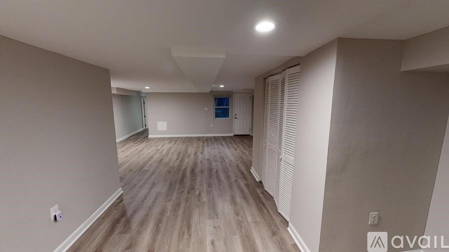 A spacious room with wooden flooring and a sliding glass door.