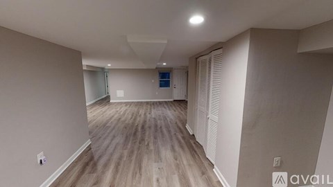 A spacious room with wooden flooring and a sliding glass door.